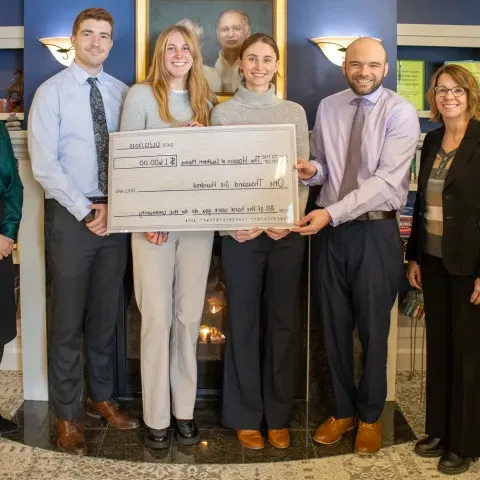 UNE medical students and local health leaders pose holding a large check in the amount of $1,600